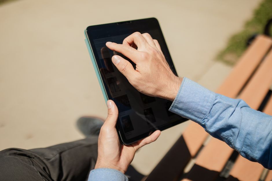 A person sits in a bright, modern living room and uses a tablet to browse a real estate application, symbolizing consumer empowerment and access to information.